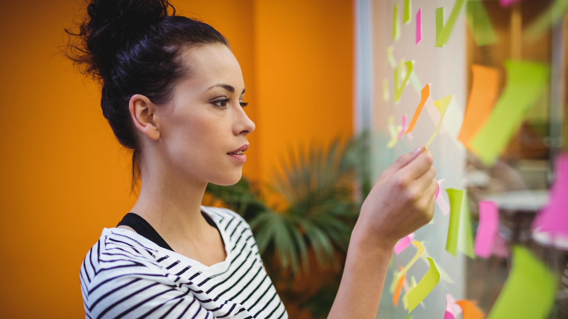 Mujer acomodando post-its en pizarrón magnético