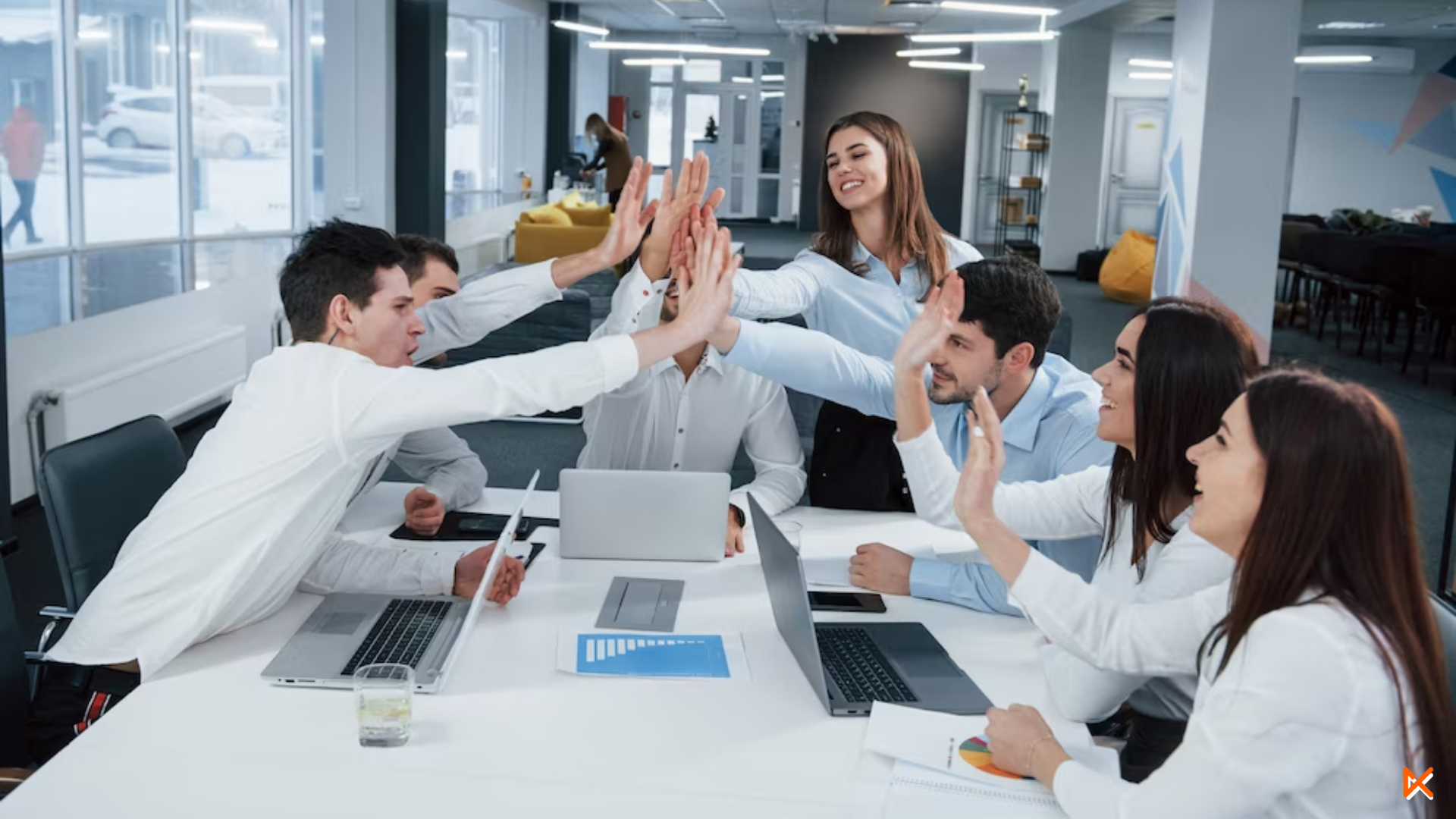 Equipo de trabajo confirmado por hombres y mujeres choca sus palmas demostrando ser un equipo unido y feliz. Todos sonríen. 