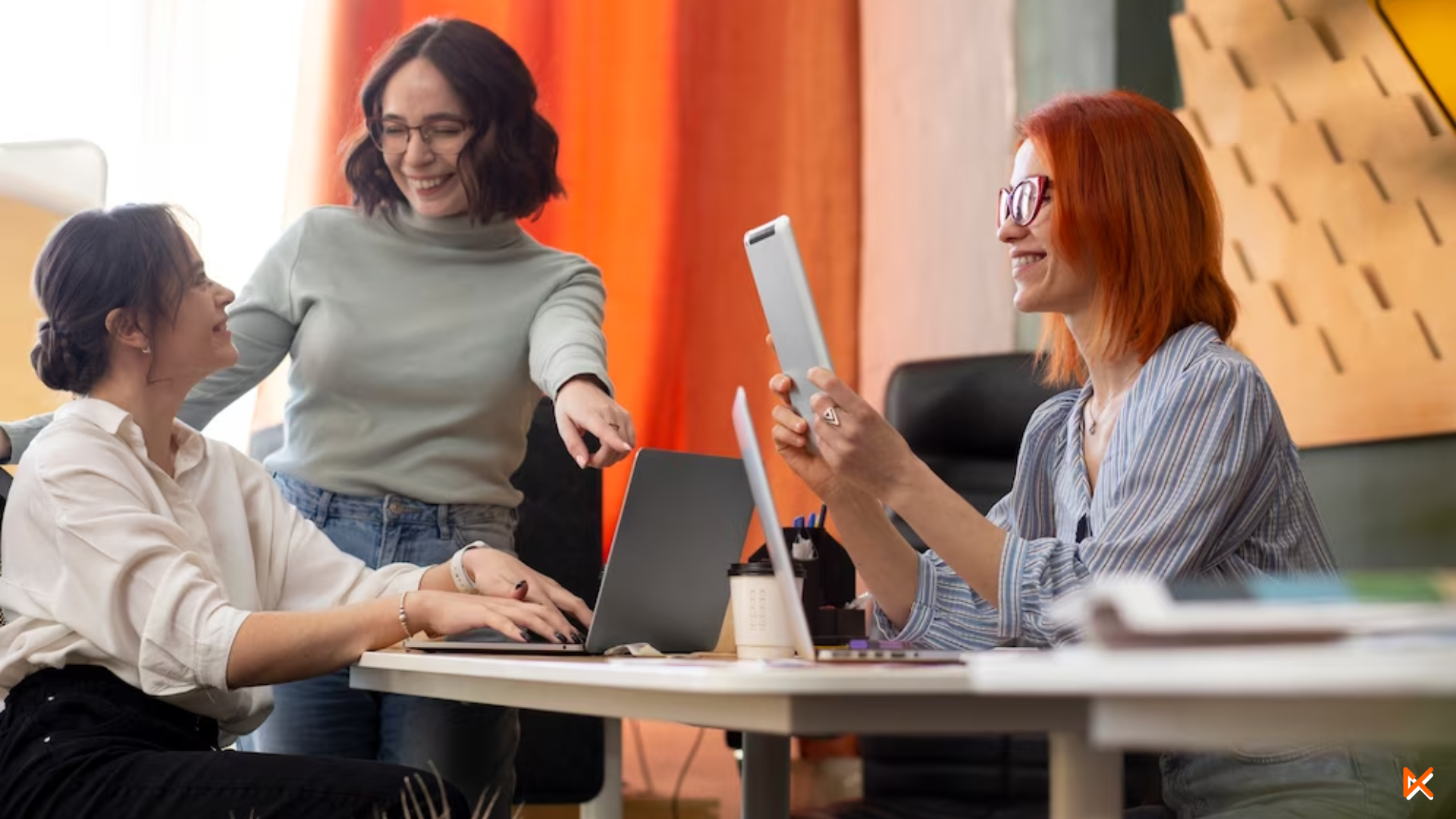 3 mujeres en una sala de juntas revisando la viabilidad de un proyecto. todas sonrién y se muestran felices.